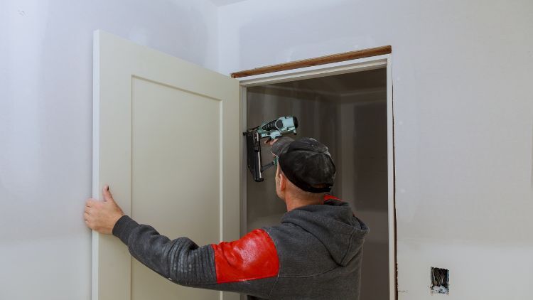 https://handymanconnection.com/wp-content/uploads/2026/03/Repairman-Fixing-Door-Standing.jpg