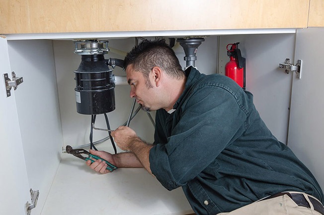 https://handymanconnection.com/wp-content/uploads/2021/05/bigstock-Plumber-Fixing-A-Garbage-Dispo-69022558.jpg