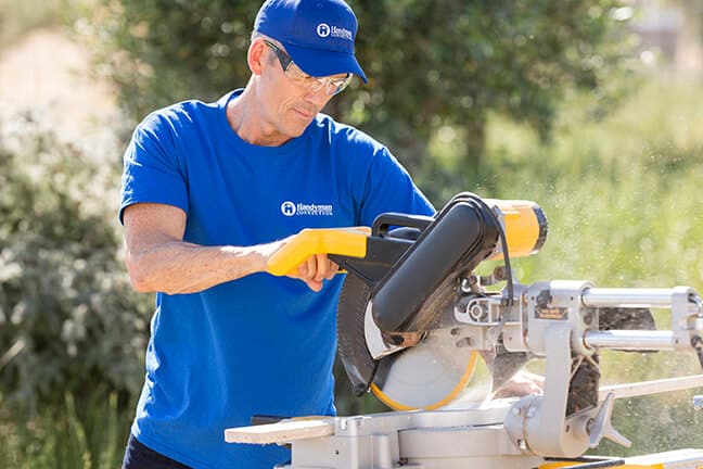 handyman doing carpentry services for a home using a power saw